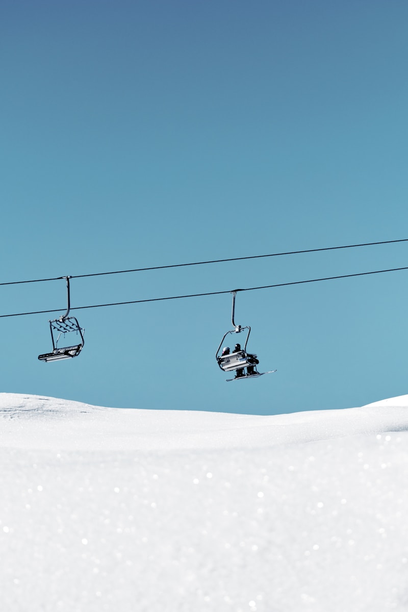 a ski lift with two skiers going up a snowy hill